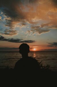 A boy is seen in silhouette against a sunset